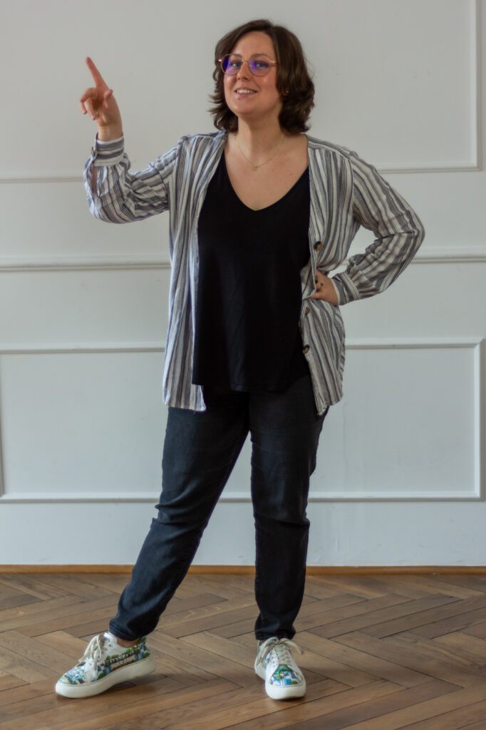 Cała postać młodej kobiety z palcem wskazującym w lewo